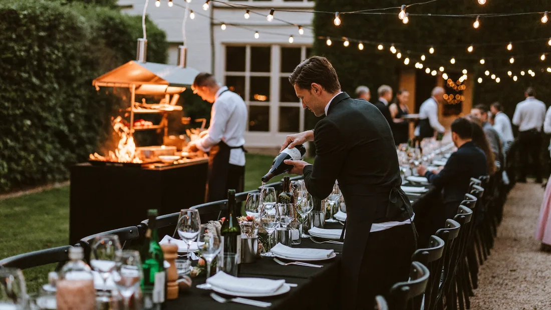 Festlich gedeckte Event-Tafel mit Service unter Lichterketten
