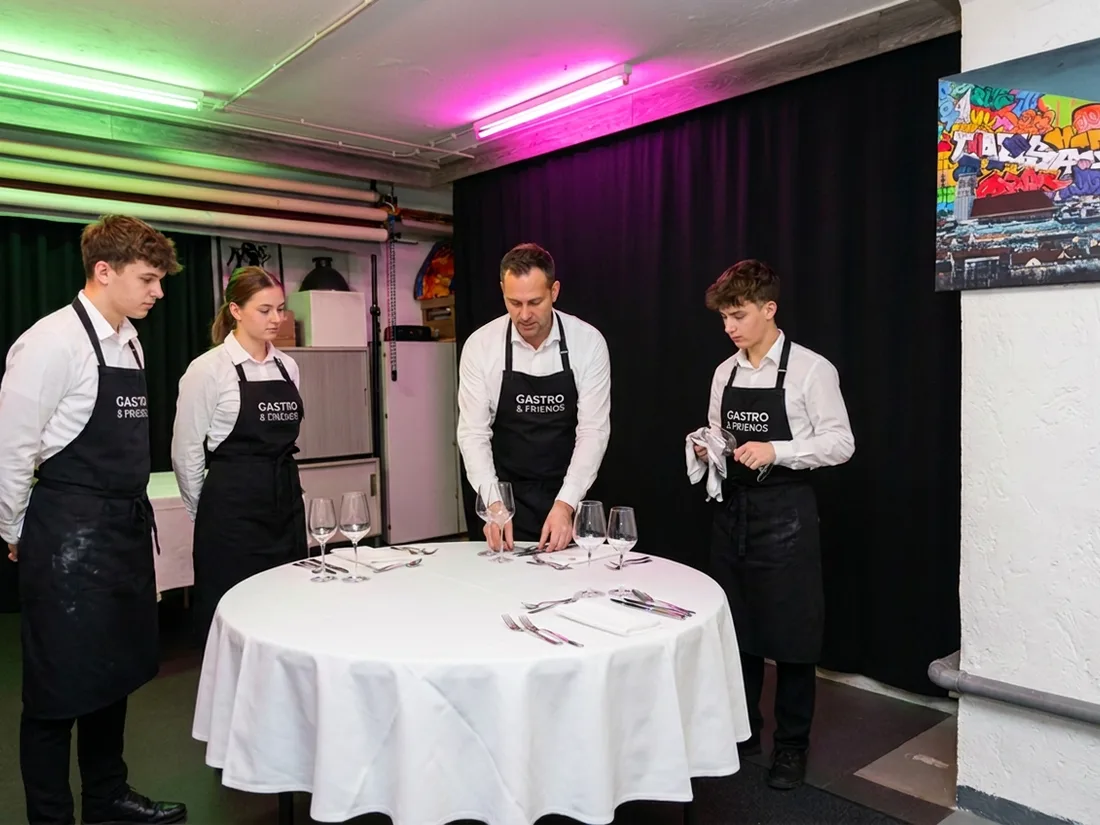 Serviceschulung im Studio — Trainer zeigt das korrekte Eindecken eines Banketttischs